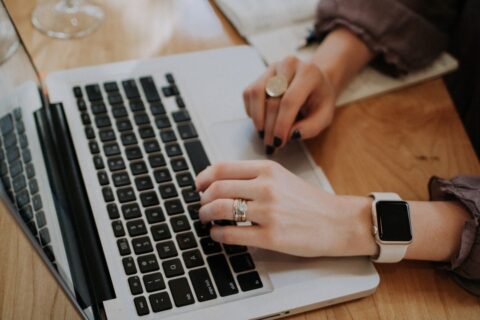Person skriver och granskar text på en bärbar dator vid ett skrivbord