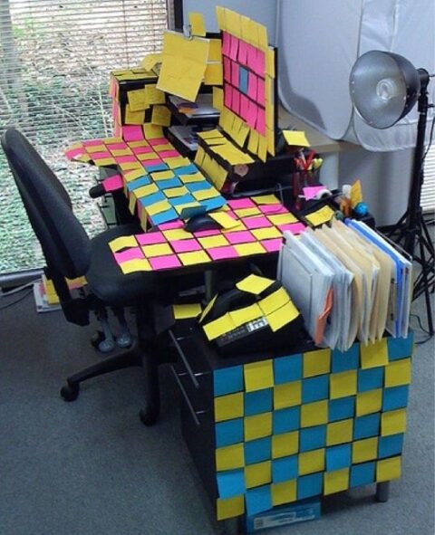 Färgglada post-it-lappar täcker ett skrivbord och en planeringstavla