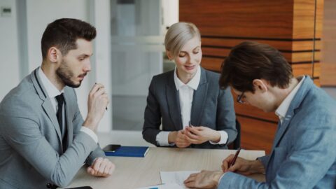 Tre affärspersoner diskuterar ett dokument vid ett bord